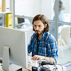 Junger Mann arbeitet konzentriert am Computer in einem B&uuml;ro
